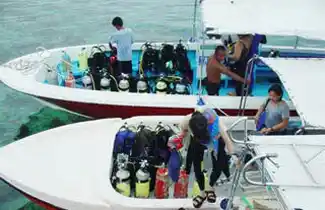 Dive crew and guests loading gear onto speed boats at Borneo Divers Mabul Resort, fully equipped for a day of premium scuba diving.