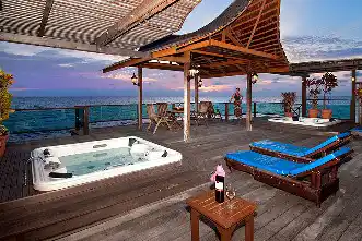 Expansive private sundeck of the Royale Villa at Mabul Water Bungalows, featuring a jacuzzi and lounge chairs for watching the sunset over the ocean.