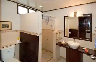 Modern and spacious luxury bathroom inside an overwater chalet at Mabul Water Bungalows, featuring a vessel sink and a separate walk-in shower.