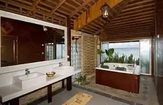 Luxurious spa-style bathroom at Mabul Water Bungalows, featuring a double vanity and a large jacuzzi tub with a view, perfect for a honeymoon retreat.