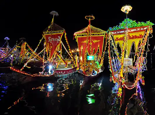 See the beautiful boats illuminated during the festival. Ornately decorated traditional Lepa boats illuminated with festive lights, creating a beautiful reflection on the water during the Regatta Lepa festival in Semporna at night.
