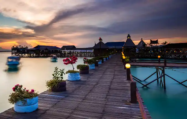 Enjoy beautiful sunsets from our budget resort jetty. Beautiful sunset view from the illuminated wooden jetty at Singamata Adventures & Reef Resort, a budget over-the-water resort near Semporna.