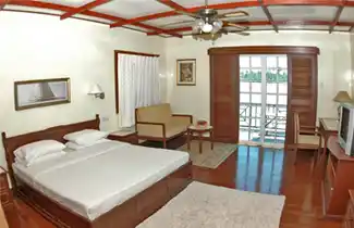 Spacious and comfortable room at Sipadan Inn in Semporna, with a large bed, seating area, and a balcony with a view of the waterfront.