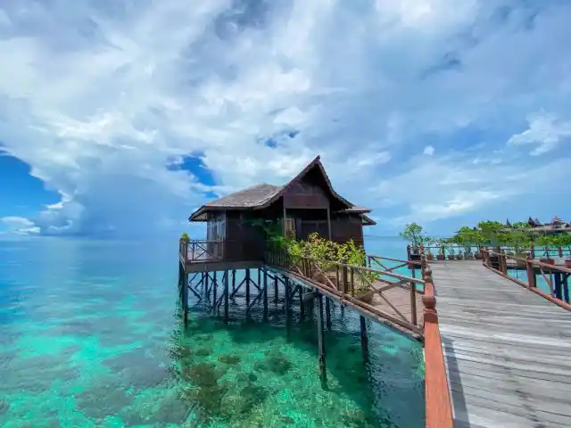 Charming Deluxe Cottage on stilts at Sipadan Water Village offers a peaceful retreat where divers relax above Mabul's clear lagoon.