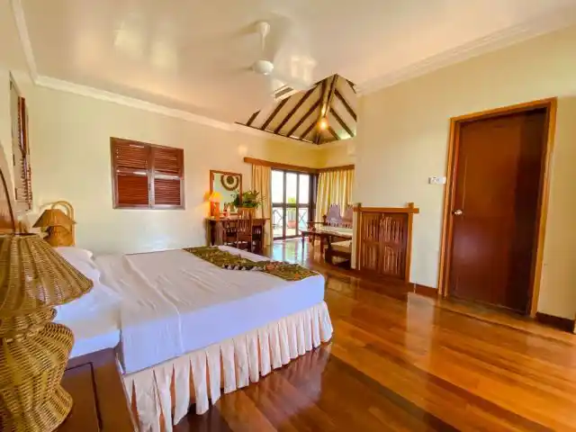 Beautifully appointed Deluxe Cottage at Sipadan Water Village, with gleaming hardwood floors, a high ceiling, and a private balcony overlooking the sea.