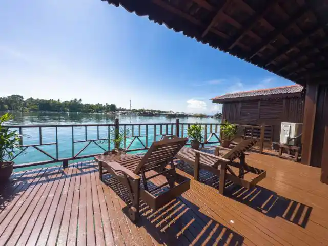 Grand Deluxe Cottage deck at Sipadan Water Village, with loungers overlooking the lagoon, is perfect for divers resting after thrilling dives.