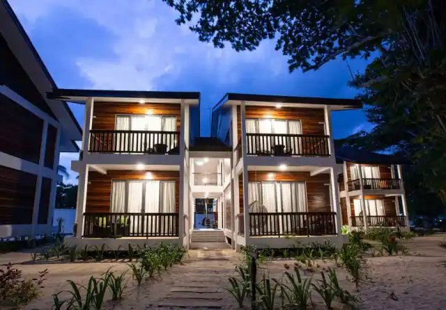 Modern two-story villas at Borneo Divers Mabul Resort, beautifully illuminated against the deep blue twilight sky.