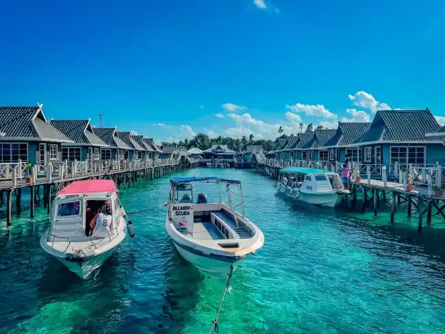 Dive boats moored between rows of wooden chalets at Billabong Scuba's backpacker lodge on Mabul Island, ready for a day of exploring Sipadan.