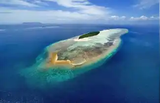 Breathtaking aerial view of the private Mataking Island Dive Resort, showcasing its extensive coral reefs, white sand beaches, and luxury 5-star amenities.