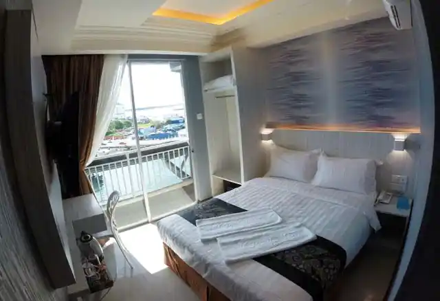 Clean and modern room at the Pacific Inn Semporna, with a comfortable double bed and a private balcony overlooking the waterfront.