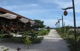 Sandy pathway leading past the beachfront chalets at Scuba Junkie Mabul Resort, a popular mid-range dive resort on Mabul Island.