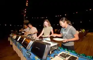Guests enjoying the evening buffet dinner on the open-air deck of the Seaventures Dive Rig restaurant.