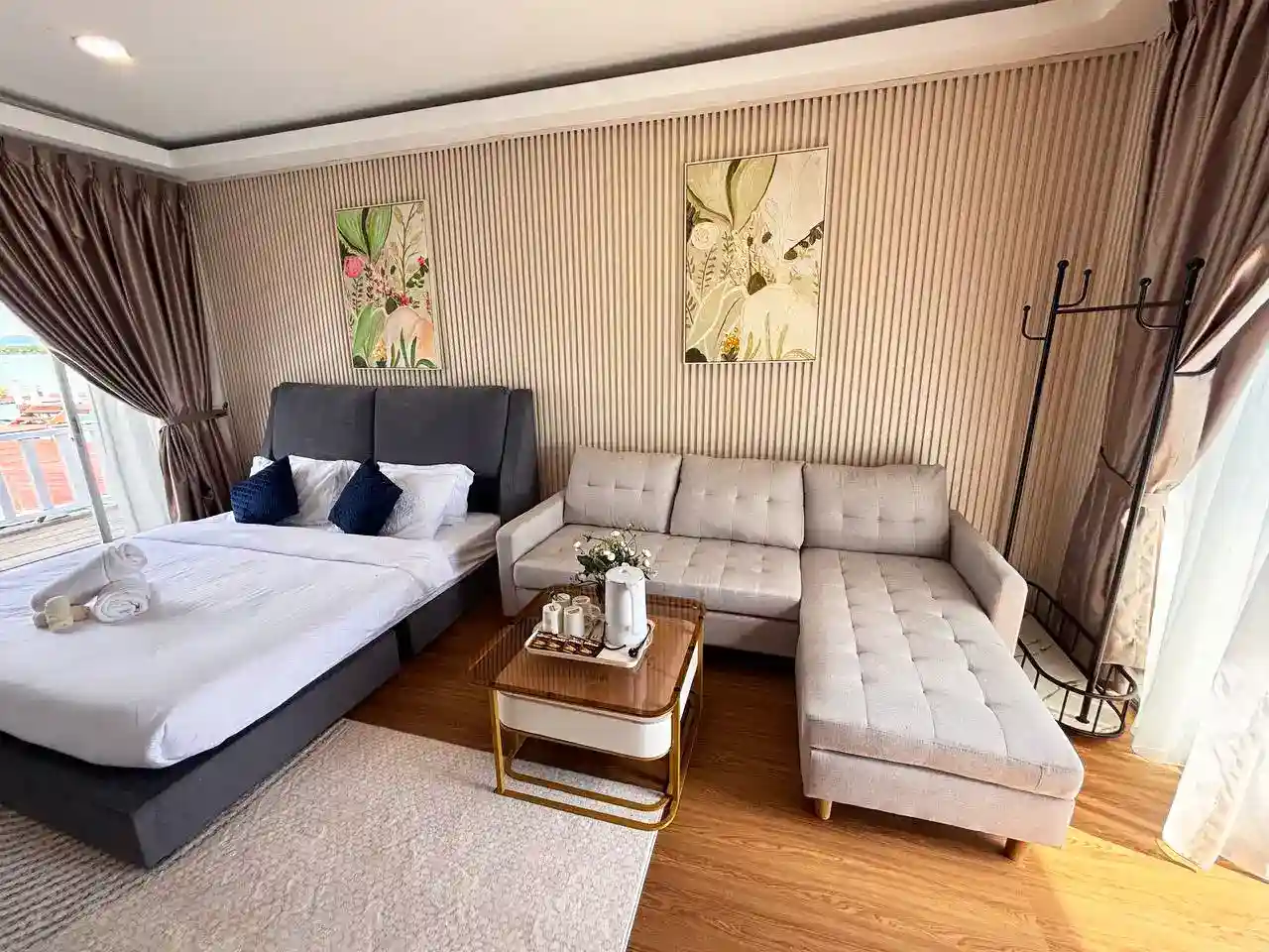Modern and stylish bedroom at Blue Ocean Resort, featuring a comfortable double bed, a sectional sofa, and contemporary decor for a relaxing stay.