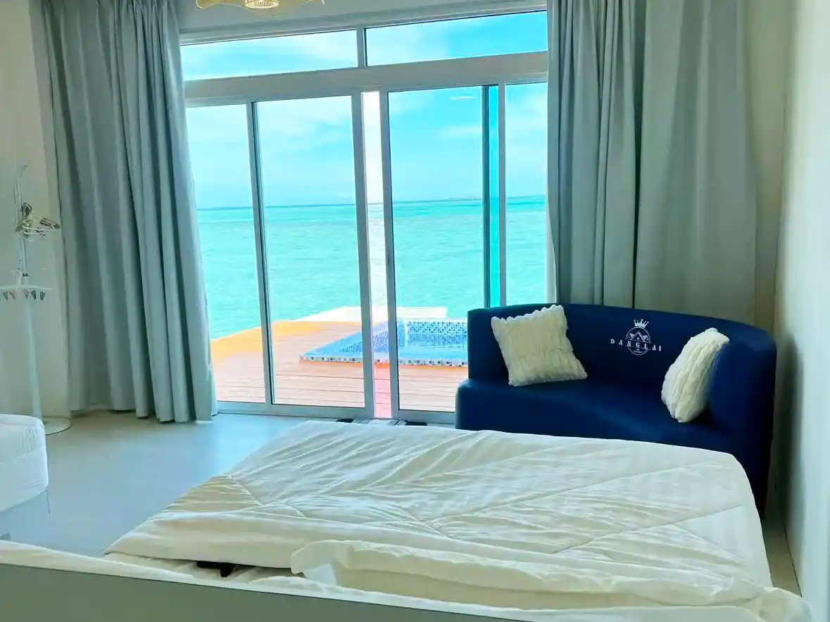 Bright and modern guest room at Danglai Resort with a large glass door opening directly onto a private deck over the turquoise sea.