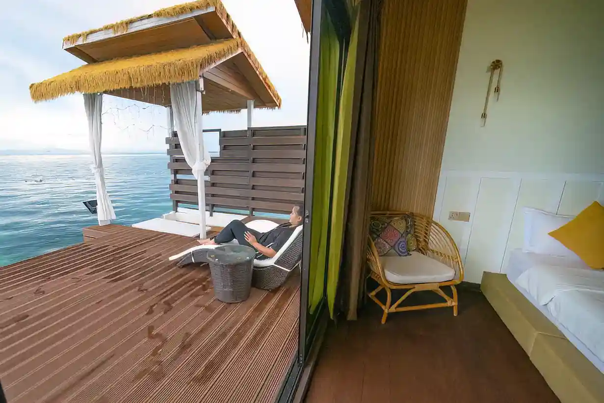 Guest relaxing on a private, covered balcony at Dayang Resort, enjoying the serene sea views directly from their overwater chalet.