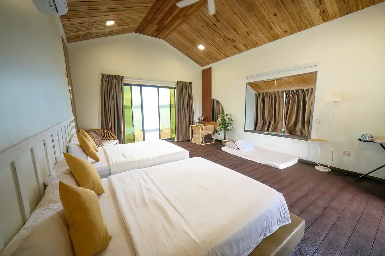Spacious and airy bedroom in a chalet at Dayang Resort, featuring a high vaulted wood ceiling and direct access to a private balcony.
