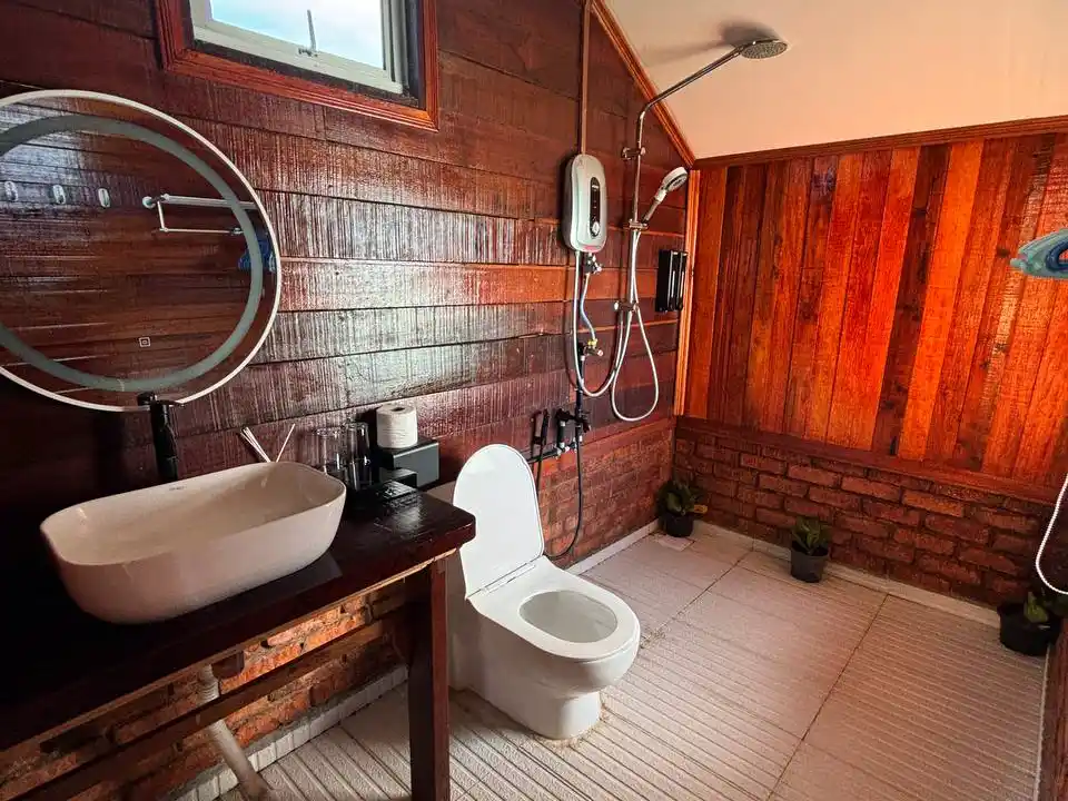 Rustic yet modern bathroom in a chalet at Larapan Water Village, featuring a stylish vessel sink and wood-paneled walls.
