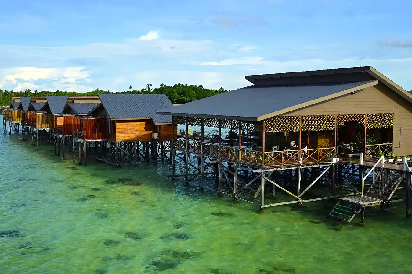 Peaceful overwater chalets of Larapan Water Village, a serene resort near Semporna known for its beautiful sunrise views over the clear sea.