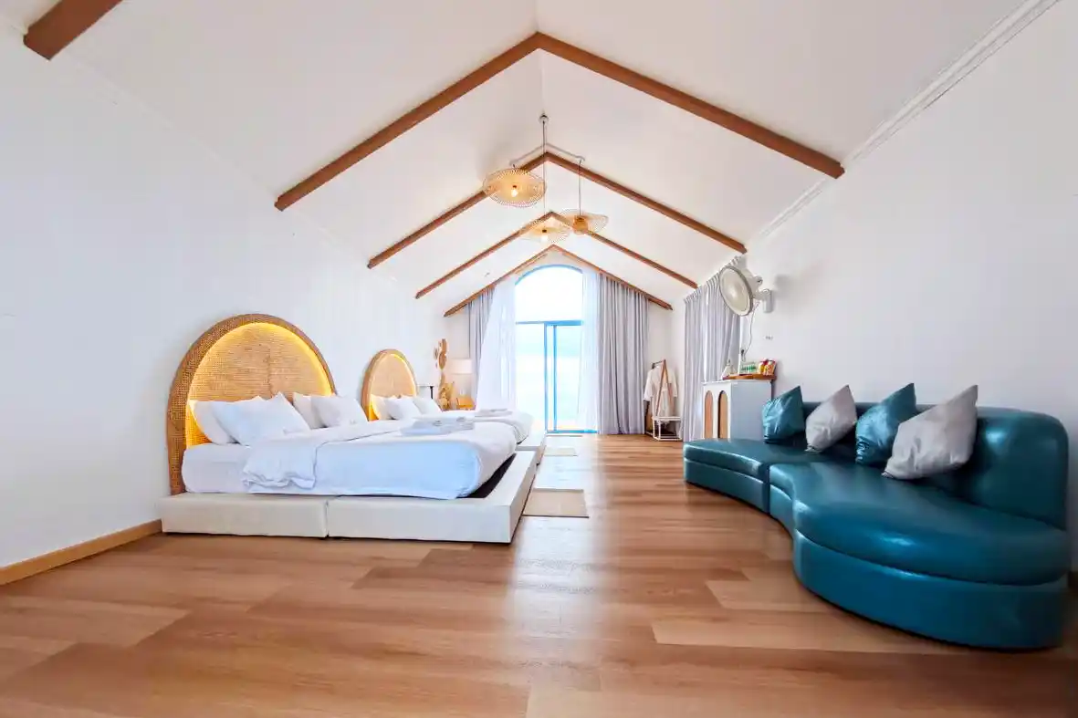 Spacious and airy bedroom at Royal Resort Semporna, with a high vaulted ceiling, stylish wicker headboards, and a large arched window with sea views.