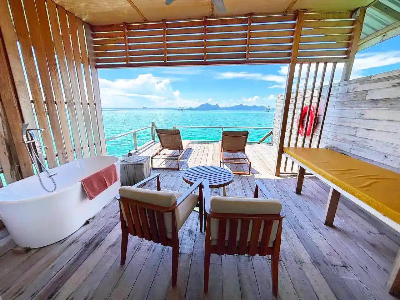 Ultimate romantic balcony at Sisipan Island Resort, complete with a freestanding bathtub, sun loungers, and a breathtaking open-air view of the Celebes Sea.