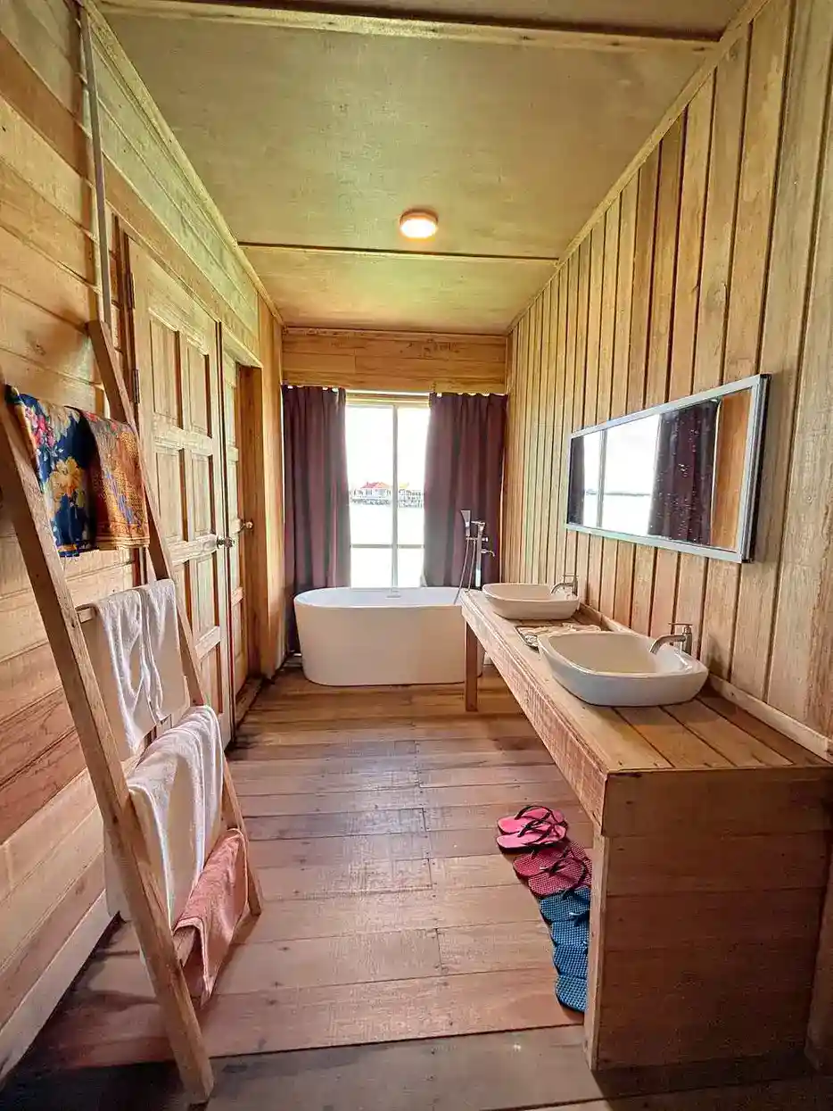 Beautiful wood-paneled bathroom at Sisipan Island Resort, featuring a double vanity, a freestanding bathtub, and a rustic ladder towel rack.