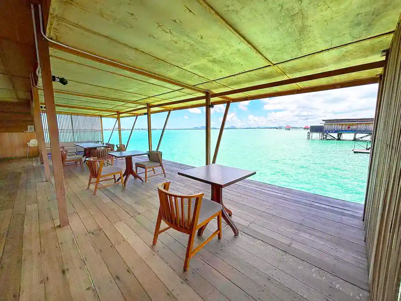 Simple and serene open-air restaurant deck at Sisipan Island Resort, offering a peaceful spot to dine right over the turquoise water.