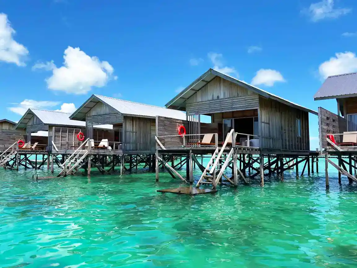 Rustic overwater chalets at the secluded Sisipan Island Resort, each with direct stair access to the inviting turquoise sea, perfect for a romantic escape.