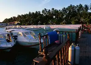 Dive boats moored at the jetty of Sipadan-Mabul Resort (SMART) in the warm morning light, with scuba tanks ready for a day of adventure.
